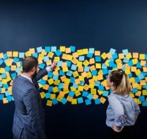 general picture of a couple of employees looking at a wall full of sticky notes