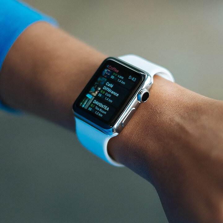 Close-up shot of a person's wrist wearing a silver Apple Watch with a white band