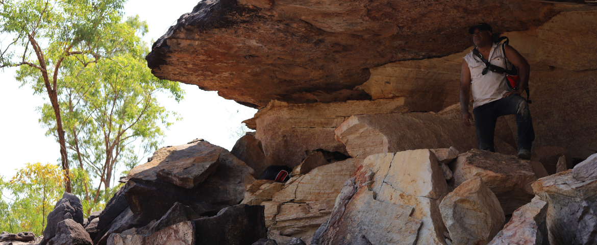 man standing under rocks