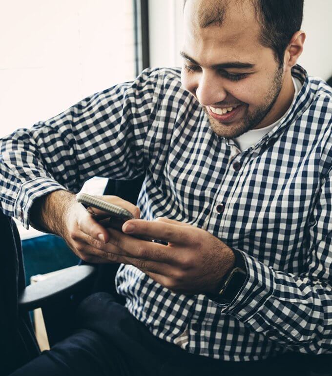 man smiling looking at his phone in his hand