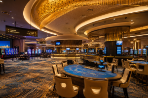 interior view of modern casino showing card table underneath a large golden lit round feature on ceiling. No people in the image